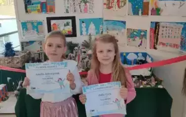 Dziewczynki pozują z dyplomami do zdjęcia 