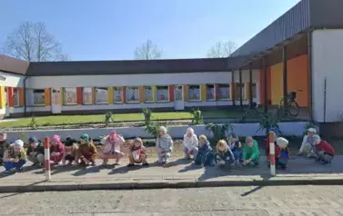 Dzieci pozują do zdjęć z zasadzonymi na terenie plac&oacute;wki drzewami i krzewami