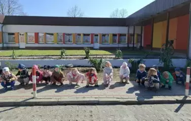 Dzieci pozują do zdjęć z zasadzonymi na terenie plac&oacute;wki drzewami i krzewami