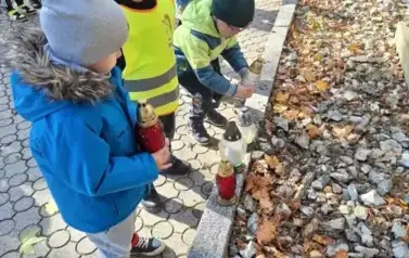 Dzieci stawiają znicze na grobach poległych żołnierzy