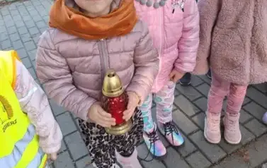 Dzieci stawiają znicze na grobach poległych żołnierzy