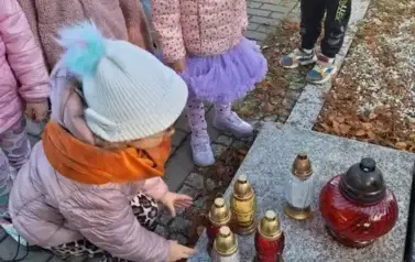 Dzieci stawiają znicze na grobach poległych żołnierzy