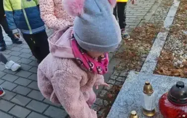Dzieci stawiają znicze na grobach poległych żołnierzy