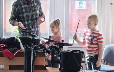 Prowadzący uczy dzieci gry na instrumencie