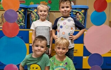 Grupa chłopc&oacute;w pozuje w kropkowej foto budce 
