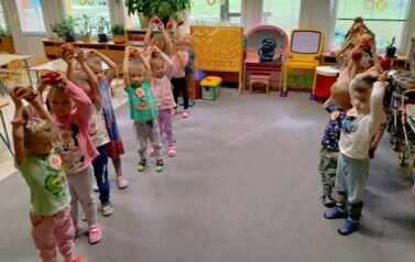 dzieci z grupy wiewi&oacute;rek podnoszą jabłka nad głową