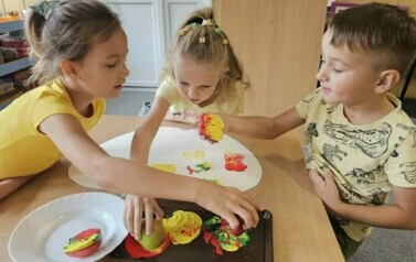 dzieci z grupy starszak&oacute;w robią prace plastyczną przy pomocy jabłkowych stempli 