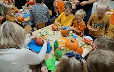 Rodzice z dziećmi tworzą dyniowe stworki 
