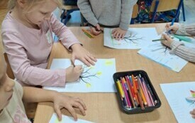 Dzieci tworzą przy stoliku swoje prace plastyczne