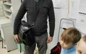 NACZELNIK POCZTY POKAZUJE DZIECIOM TORBĘ LISTONOSZA.