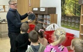 KIEROWNIK POCZTY POKAZUJE SŁONECZKOM GĄBKĘ Z TUSZEM DO STEMPLOWANIA LIST&Oacute;W.