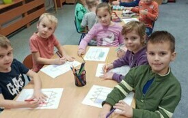 KRASNOLUDKI PRZY STOLIKU WYKONUJĄ PRACEE PLASTYCZNĄ Z OKAZJI DNIA KREDKI.