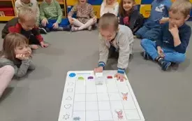 Dzieci obserwują jak zakodowany Genibot jeździ po macie do kodowania