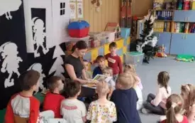 Absolwentka czyta bajkę w grupie krasnali