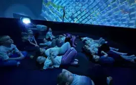 DZIECI OGLADAJĄ FILM EDUKACYJNY W KINIE SFERYCZNYM.