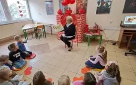 Dzieci siedzą i słuchają Pani bibliotekarki 