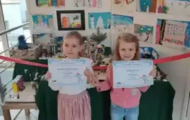 Dziewczynki pozują z dyplomami do zdjęcia 