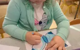 DZIEWCZYNKA MALUJE KREDKAMI SZABLON MOTYLKA