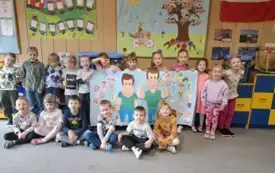 ZDJĘCIE GRUPOWE ZAJĄCZK&Oacute;W. DZIECI PREZENTUJĄ PRACĘ PLASTYCZNĄ