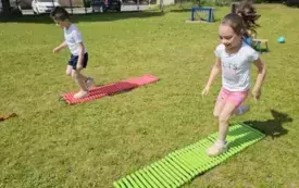 DZIECI BIEGNĄ PRZEZ DRABINKĘ GIMNASTYCZNĄ