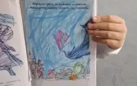 Chłopiec pozuje z pracą plastyczną