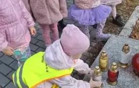 Dzieci stawiają znicze na grobach poległych żołnierzy