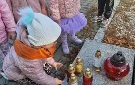 Dzieci stawiają znicze na grobach poległych żołnierzy