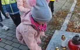 Dzieci stawiają znicze na grobach poległych żołnierzy