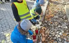 Dzieci stawiają znicze na grobach poległych żołnierzy
