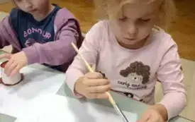 PRACA PLASTYCZNA W GRUPIE BIEDRONKI - DZIEWCZYNKA MALUJE KUBECZEK