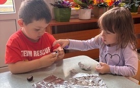 DZIECI OWIJAJĄ FOLIĄ ALUMINIOWĄ KASZTANY