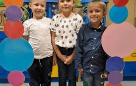 Dziewczynka i chłopcy w grupy zajączk&oacute;w pozują w foto budce 