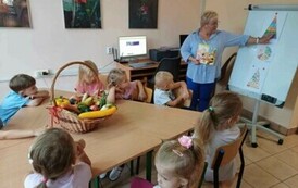 Pani bibliotekarka omawia z dziećmi piramidę zdrowego odżywiania się