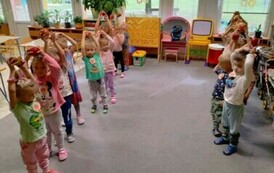 dzieci z grupy wiewi&oacute;rek podnoszą jabłka nad głową