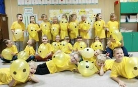 Grupa słoneczek pozuje do zdjęcia z uśmiechnietymi balonami