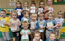 Grupa motylk&oacute;w pozuje do wsp&oacute;lnego zdjęcia z pracami plastycznymi