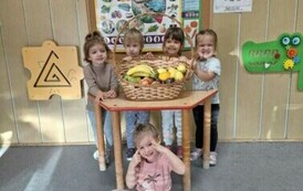 Dziewczynki z grupy maluch&oacute;w pozują z koszem pełnym owoc&oacute;w