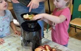 dziewczynka razem z nauczycielką wyciska sok z owoc&oacute;w