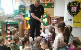 FUNKCJONARIUSZ STRAŻY MIEJSKIEJ ROZDAJE DZIECIOM UPOMINKI - OPASKI ODBLASKOWE