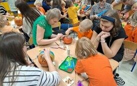 Dzieci wraz z rodzicami wsp&oacute;lnie ozdabiają dynie 