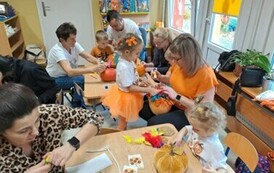 Dzieci z rodzicami ozdabiają dynie 