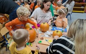 Rodzice z dziećmi tworzą dyniowe stworki 