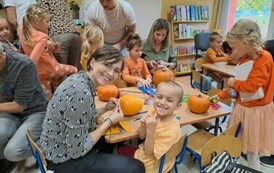 Dziecko z rodzicem ozdabia dynie 