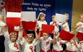 DZIECI TWORZĄ Z KOLOROWYCH KARTONIK&Oacute;W FLAGĘ POLSKI.