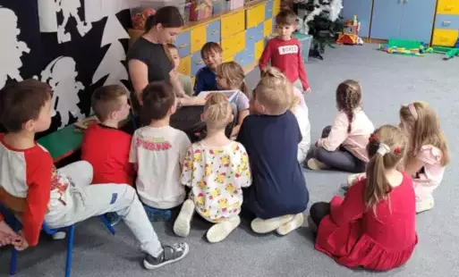 Dzieci słuchają bajki czytanej przez absolwentkę